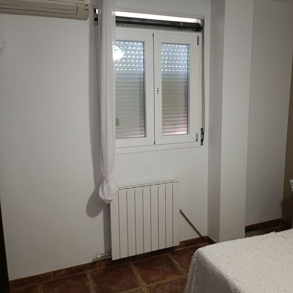 Ventana doble abatible con persiana enrollable y marco blanco