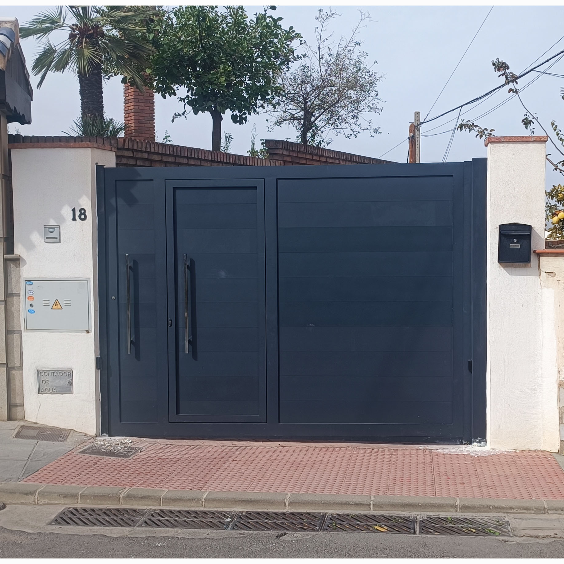 Puerta de acceso gris con entrada peatonal integrada