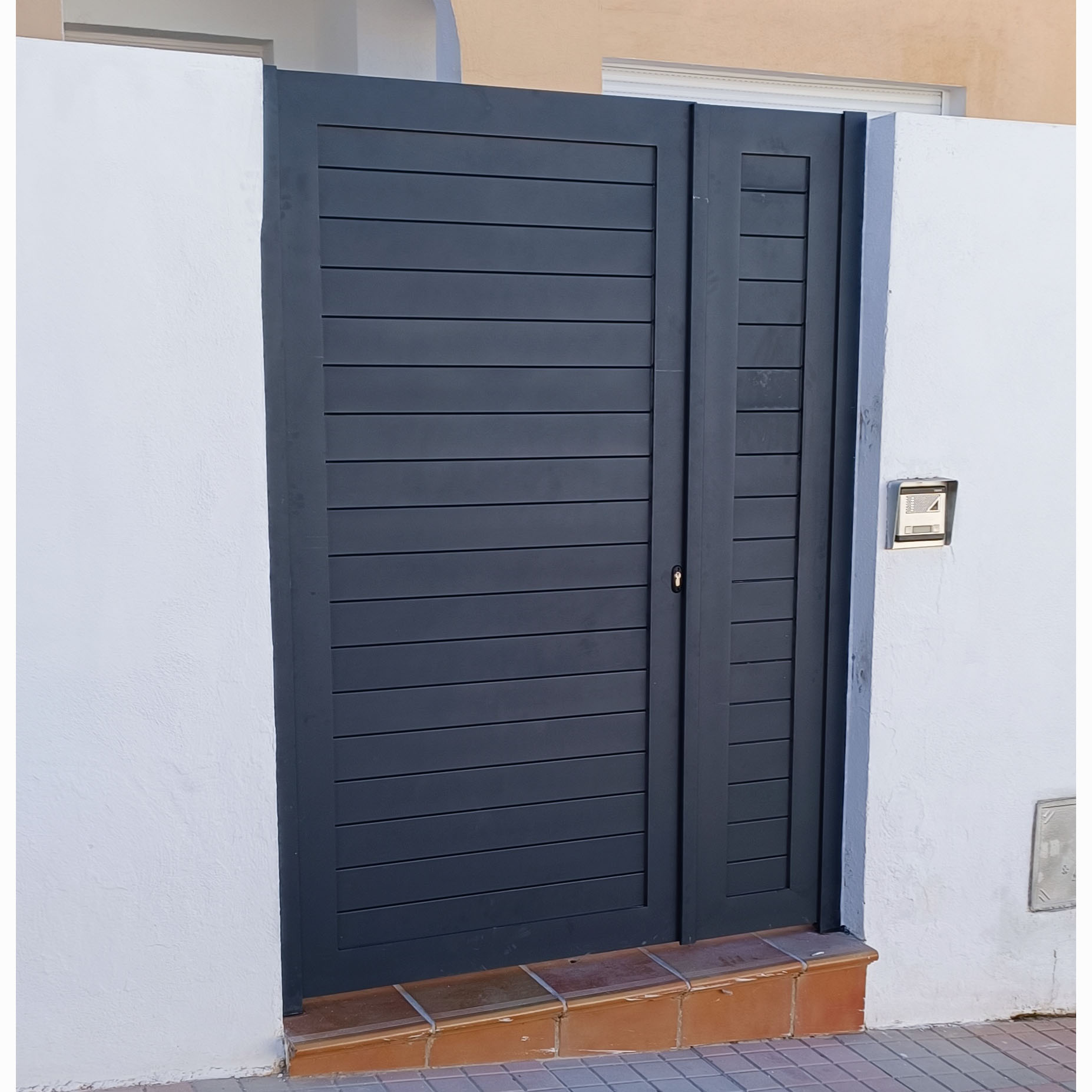Puerta peatonal en gris oscuro con diseño de líneas horizontales